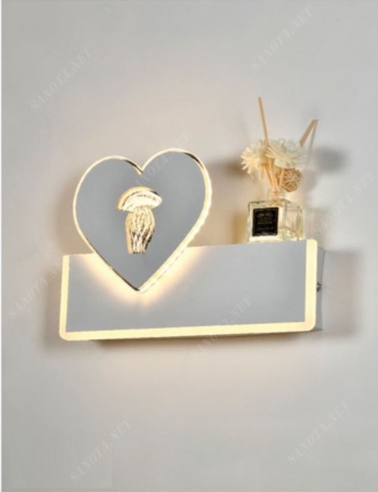 một chiếc đèn LED gắn tường có thiết kế là một hộp đèn vững chắc kết hợp với đó là điểm nhấn là một khung đèn hình trái tim có mặt trăng bằng kim loại được đính trên đó. Khi chiếc đèn được bật là lúc những dãi ánh sáng dịu nhẹ đi qua từng đường nét trên chiếc đèn từ hộp đèn đến khung trái tim. Chiếc đèn hiện đại phù hợp với mọi không gian sống đặc, vừa là một vật decor vừa là chiếc đèn trang trí