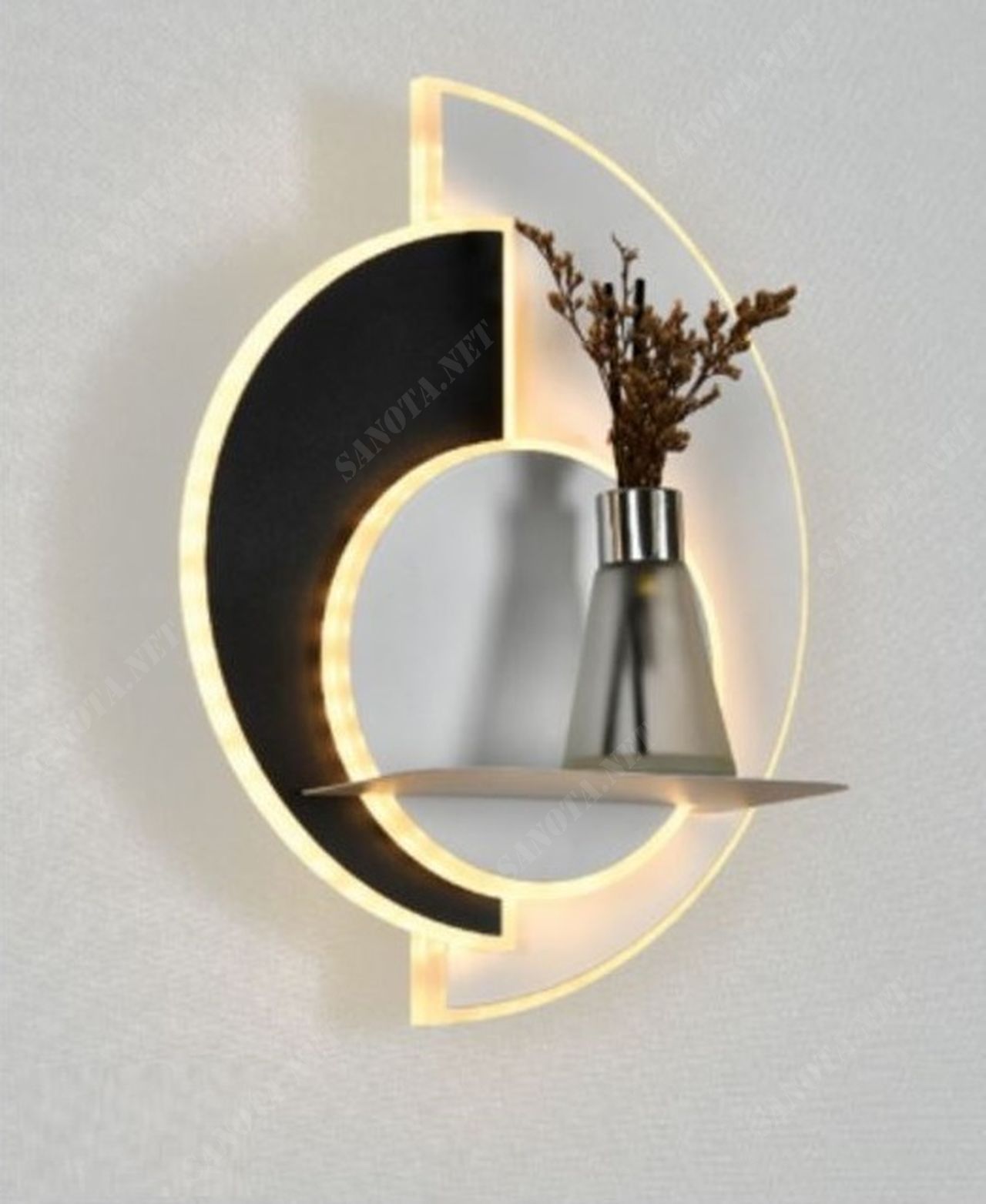 một chiếc đèn gắn tường có thiết kế độc đáo là một chiếc đèn vừa chiếu sáng vừa là vật decor cho không gian nội thất. chiếc đèn là sự kết hợp màu tinh tế giữa màu đen và trắng. cùng với đó nó còn được đính kèm thêm một tấm kệ nhỏ để có thể để những đồ vật trang trí cùng, khi chiếc đèn led được bật là lúc nó nổi bật giữa không gian nội thất, điểm nhấn cho món đồ trang trí, chiếc đèn có thể gắn ở bất kì nơi nào, những nơi cần vẻ đẹp hiện đại và phong cách