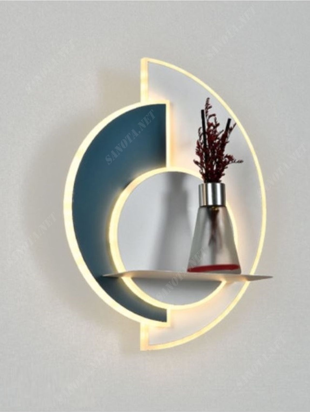 một chiếc đèn gắn tường có thiết kế độc đáo là một chiếc đèn vừa chiếu sáng vừa là vật decor cho không gian nội thất. chiếc đèn là sự kết hợp màu tinh tế giữa màu đen và trắng. cùng với đó nó còn được đính kèm thêm một tấm kệ nhỏ để có thể để những đồ vật trang trí cùng, khi chiếc đèn led được bật là lúc nó nổi bật giữa không gian nội thất, điểm nhấn cho món đồ trang trí, chiếc đèn có thể gắn ở bất kì nơi nào, những nơi cần vẻ đẹp hiện đại và phong cách