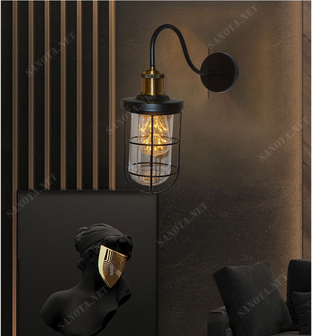 một chiếc đèn tường với thiết kế vintage tỏa sáng như một điểm nhấn đầy cá tính và sang trọng. Với thiết kế là một chiếc lồng sắt sơn tĩnh điện màu đen. Chao đèn làm từ thuỷ tinh trong suốt phát ra ánh sáng khắp cả không gian nội thất Với thiết kế linh hoạt và đa dạng, chiếc đèn này phù hợp với mọi không gian. Từ phòng khách đến phòng ngủ, từ phòng làm việc đến hành lang, và cả ngoài sân vườn. Nó đều là một điểm nhấn tuyệt vời cho bất kỳ không gian nào.