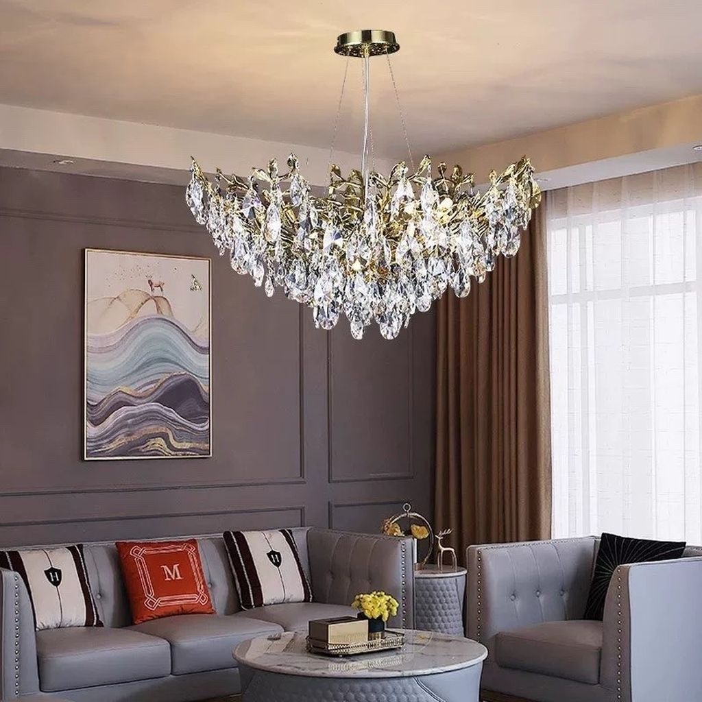 Đèn chùm trang trí phòng khách lấy cảm hứng từ những cánh lá pha lê đan xen cùng khung kim loại mạ vàng sang trọng. Chiếc đèn chùm mang đến vẻ đẹp rực rỡ, phù hợp với mọi không gian như phòng khách, sảnh lớn, biệt thự, nhà hàng hay khách sạn cao cấp. Ánh sáng phản chiếu qua từng tinh thể pha lê, tạo nên hiệu ứng lung linh ấn tượng, làm nổi bật toàn bộ không gian.