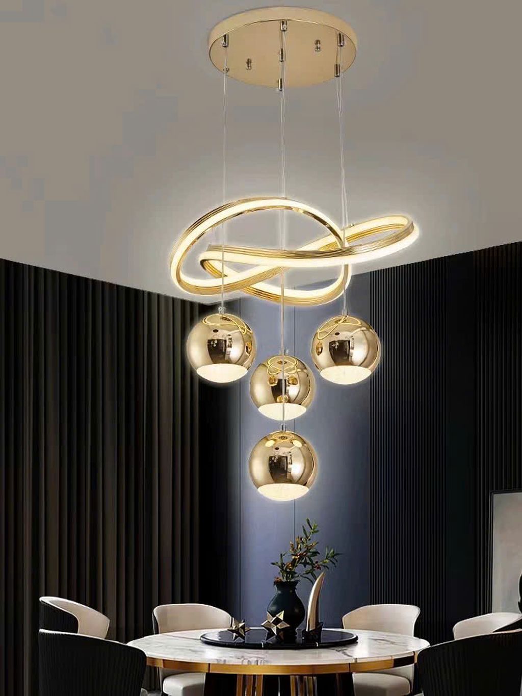 Đèn chùm nghệ thuật gây ấn tượng mạnh mẽ ngay từ cái nhìn đầu tiên với thiết kế độc đáo gồm các vòng LED ánh vàng mềm mại xoắn lượn nghệ thuật, kết hợp cùng những quả cầu ánh kim tròn trịa mang hiệu ứng gương phản chiếu đầy cuốn hút. Từng chi tiết được chế tác tỉ mỉ, mang lại cảm giác sang trọng nhưng không quá cầu kỳ. Phù hợp với các không gian hiện đại, căn hộ cao cấp, phòng khách, sảnh đón tiếp hay bàn ăn tinh tế.