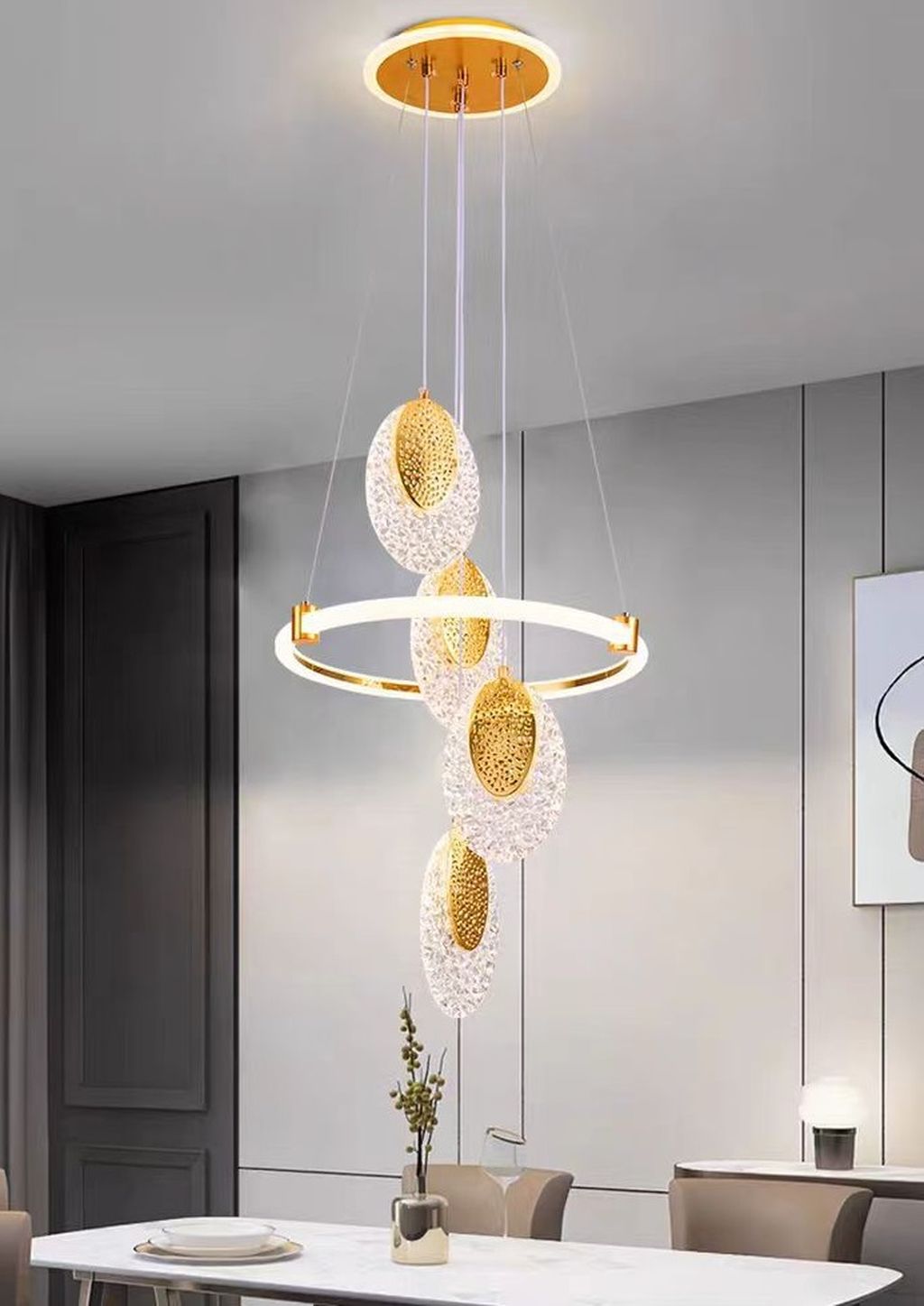 Đèn chùm pha lê là sự giao thoa hoàn hảo giữa tính nghệ thuật và công năng sử dụng. Đèn được tạo hình từ những khối pha lê trong suốt hình elip đính kèm lõi ánh kim màu vàng đồng. Mang đến hiệu ứng ánh sáng lung linh như những vầng trăng dát vàng. Bao quanh trung tâm là một vòng LED tròn hiện đại, vừa tạo điểm nhấn thị giác vừa lan tỏa ánh sáng dịu nhẹ. Làm nổi bật không gian sống một cách tinh tế.