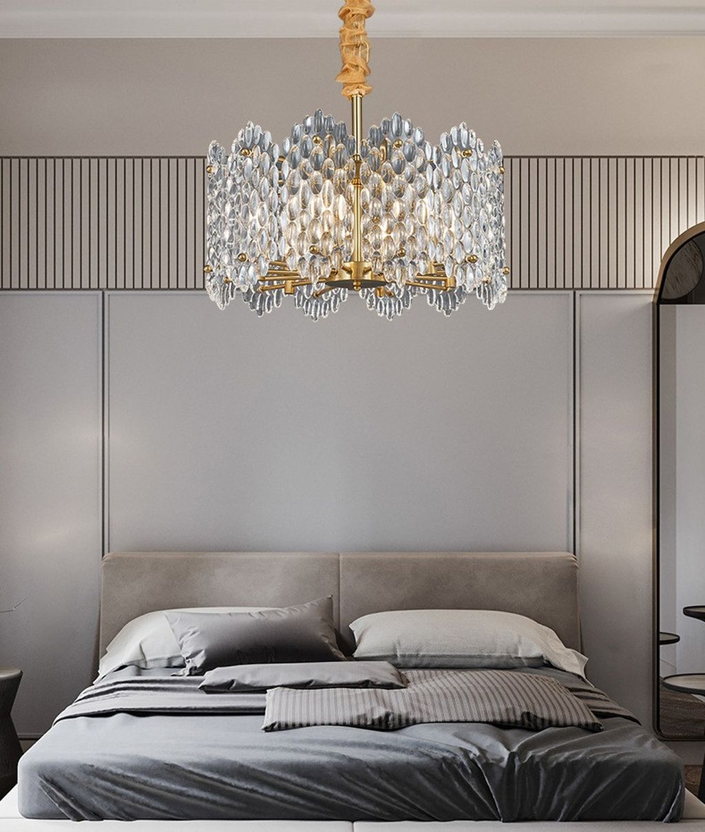 Đèn chùm thả trần này được thiết kế với kiểu dáng đối xứng, kết hợp giữa khung kim loại mạ vàng sang trọng và hệ thống pha lê cao cấp, tạo nên một tổng thể hài hòa, thanh lịch nhưng vẫn đầy cá tính. Các hạt pha lê được cắt gọt tỉ mỉ như những giọt sương lấp lánh, mỗi khi ánh sáng lan tỏa, chúng phản chiếu thành những vệt sáng lung linh, đưa cả không gian nghỉ ngơi bước vào một thế giới đầy chất thơ và ấm áp.