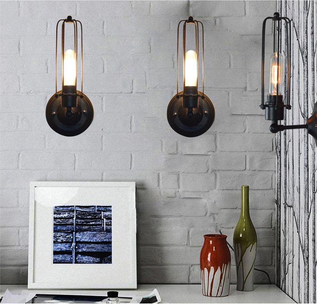 Đèn tường decor được chế tác tinh xảo với chất liệu kim loại sơn tĩnh điện màu đen mờ. Đèn gắn tường nghệ thuật này nổi bật nhờ khung đèn dạng lồng độc đáo bao bọc bóng đèn Edison mang đậm phong cách cổ điển pha lẫn hiện đại. Ánh sáng vàng ấm từ bóng LED tiết kiệm điện không chỉ tạo cảm giác ấm cúng. Mà còn giúp không gian trở nên sang trọng, gần gũi hơn. Dù được lắp đặt trong phòng khách, góc làm việc hay hành lang.