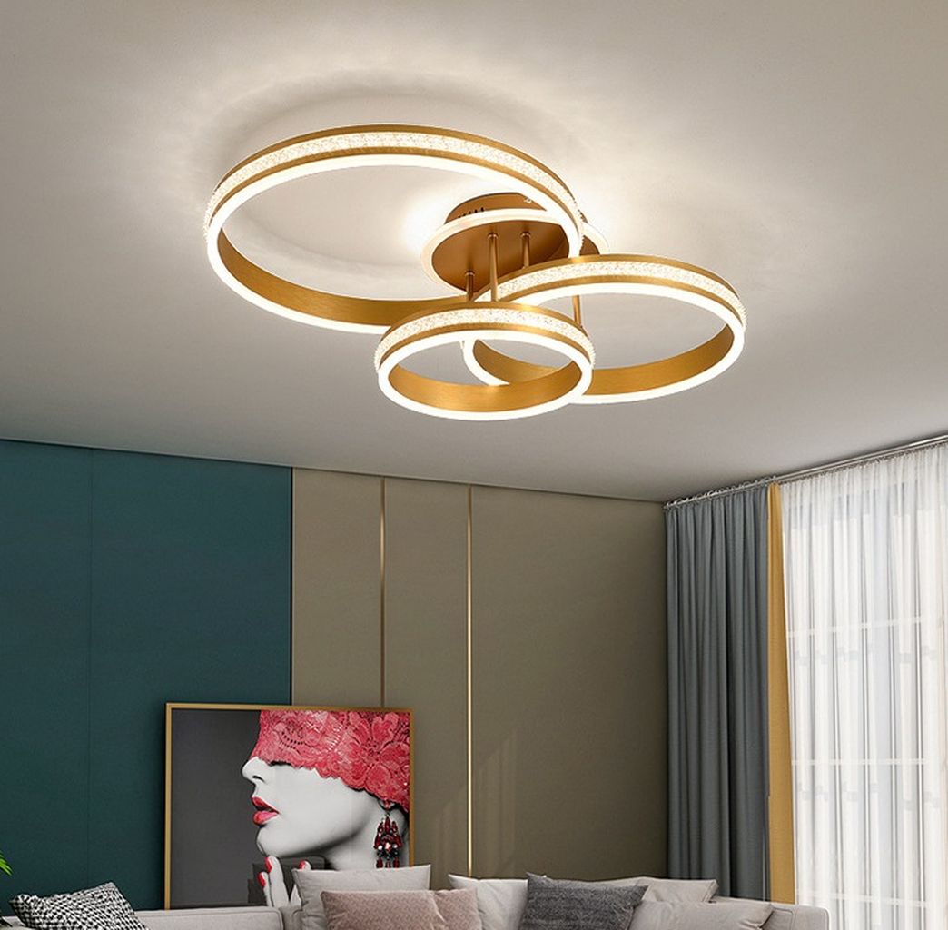 Đèn ốp trần sang trọng được thiết kế với ba vòng tròn ánh sáng đan xen độc đáo. Tạo nên hình ảnh hài hòa, cân đối nhưng không kém phần ấn tượng. Gam màu vàng champagne sang trọng kết hợp viền ánh sáng LED dịu mắt không chỉ giúp không gian bừng sáng mà còn mang lại cảm giác ấm áp, gần gũi. Chất liệu kim loại cao cấp phủ sơn tĩnh điện bền bỉ, chống oxy hóa hiệu quả, giúp đèn giữ vững vẻ đẹp qua thời gian.