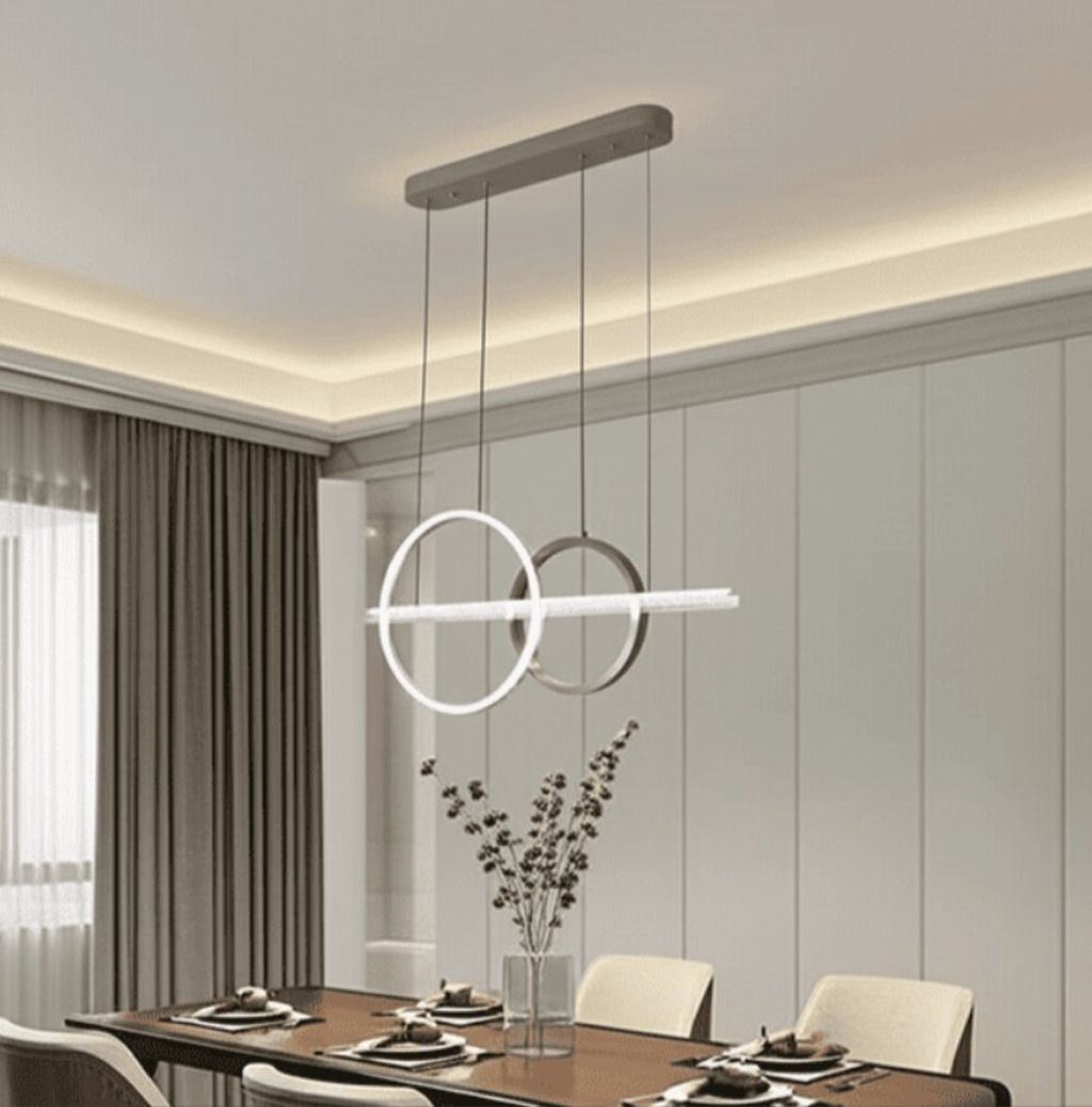 Đèn chùm hiện đại gây ấn tượng mạnh với kiểu dáng vòng tròn lồng ghép tinh tế. Kết hợp cùng thanh đèn LED ngang tạo nên một tổng thể hài hòa nhưng không kém phần độc đáo. Mỗi đường nét đều được chăm chút kỹ lưỡng, mang đậm phong cách minimalist hiện đại. Sự giao thoa giữa nghệ thuật và công năng.