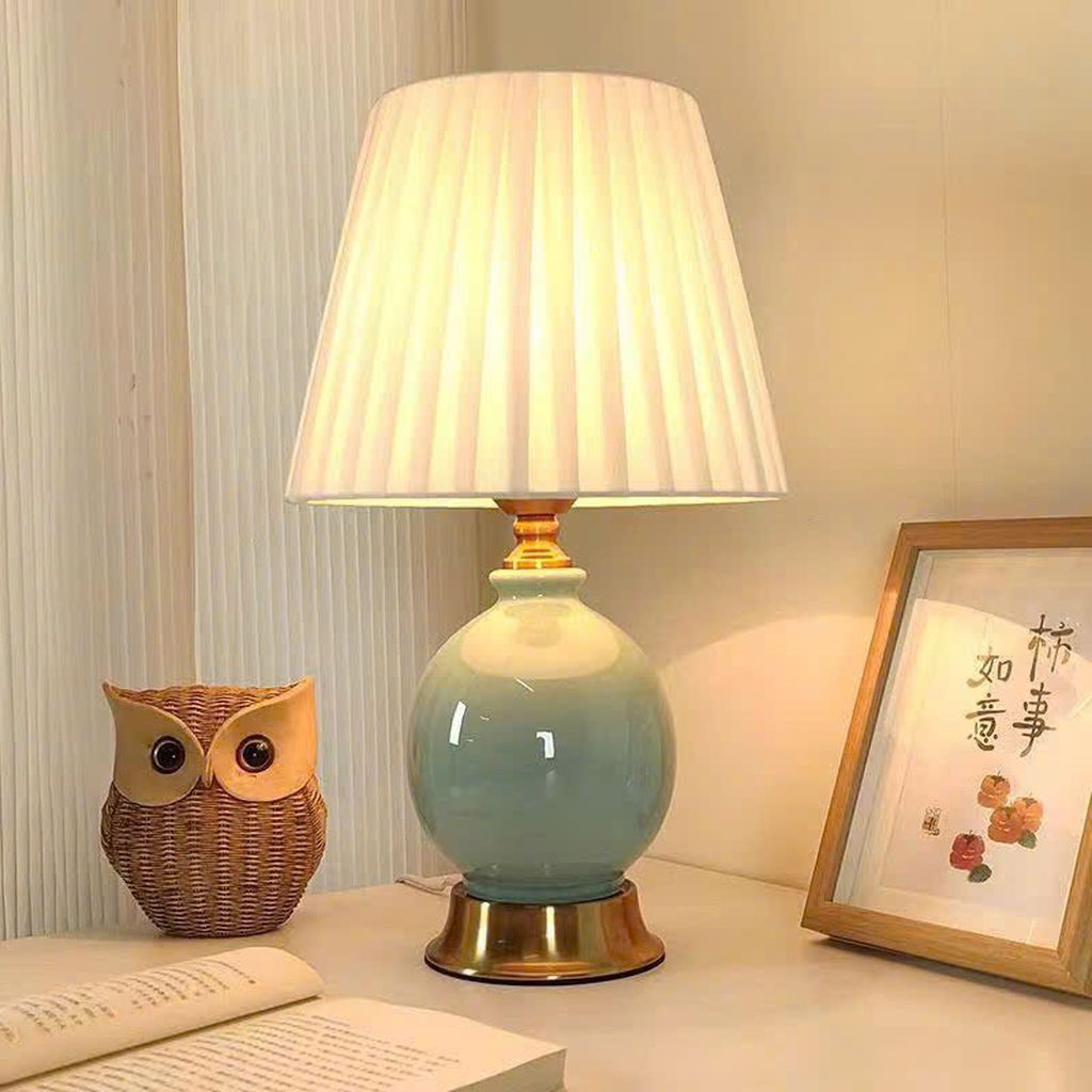 Đèn bàn gốm sứ cao cấp với điểm nhấn thu hút ánh nhìn chính là phần thân đèn được chế tác từ gốm sứ tráng men bóng loáng. Cùng gam màu chuyển sắc nhẹ nhàng, hài hòa. Tông xanh pastel nhạt kết hợp với lớp men loang tinh tế tạo hiệu ứng chiều sâu và cảm giác dịu mắt. Phù hợp với nhiều phong cách nội thất như tân cổ điển, Scandinavian, hay vintage tối giản.