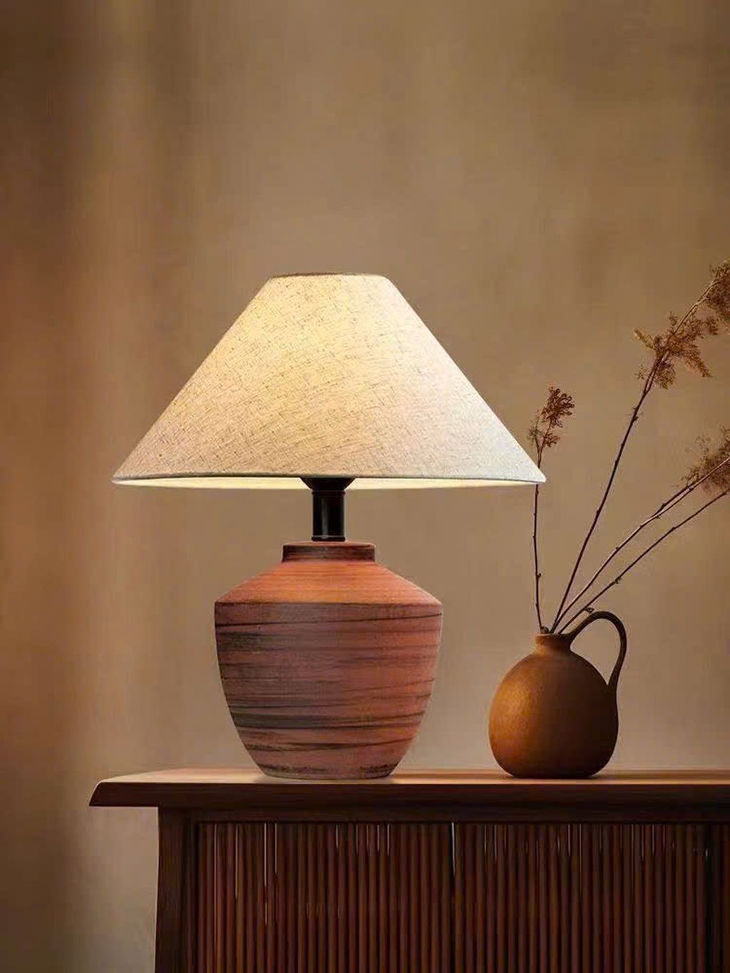 Đèn bàn vân gốm sang trọng với thân đèn được chế tác từ chất liệu gốm sứ cao cấp. Gam màu cam đất phối sọc đen tạo hiệu ứng thị giác mạnh mẽ mà vẫn giữ nét mộc mạc đặc trưng của chất liệu thủ công. Thiết kế này phù hợp với nhiều phong cách nội thất. Từ Scandinavian tối giản, phong cách Nhật trầm lắng đến không gian hiện đại đương đại.