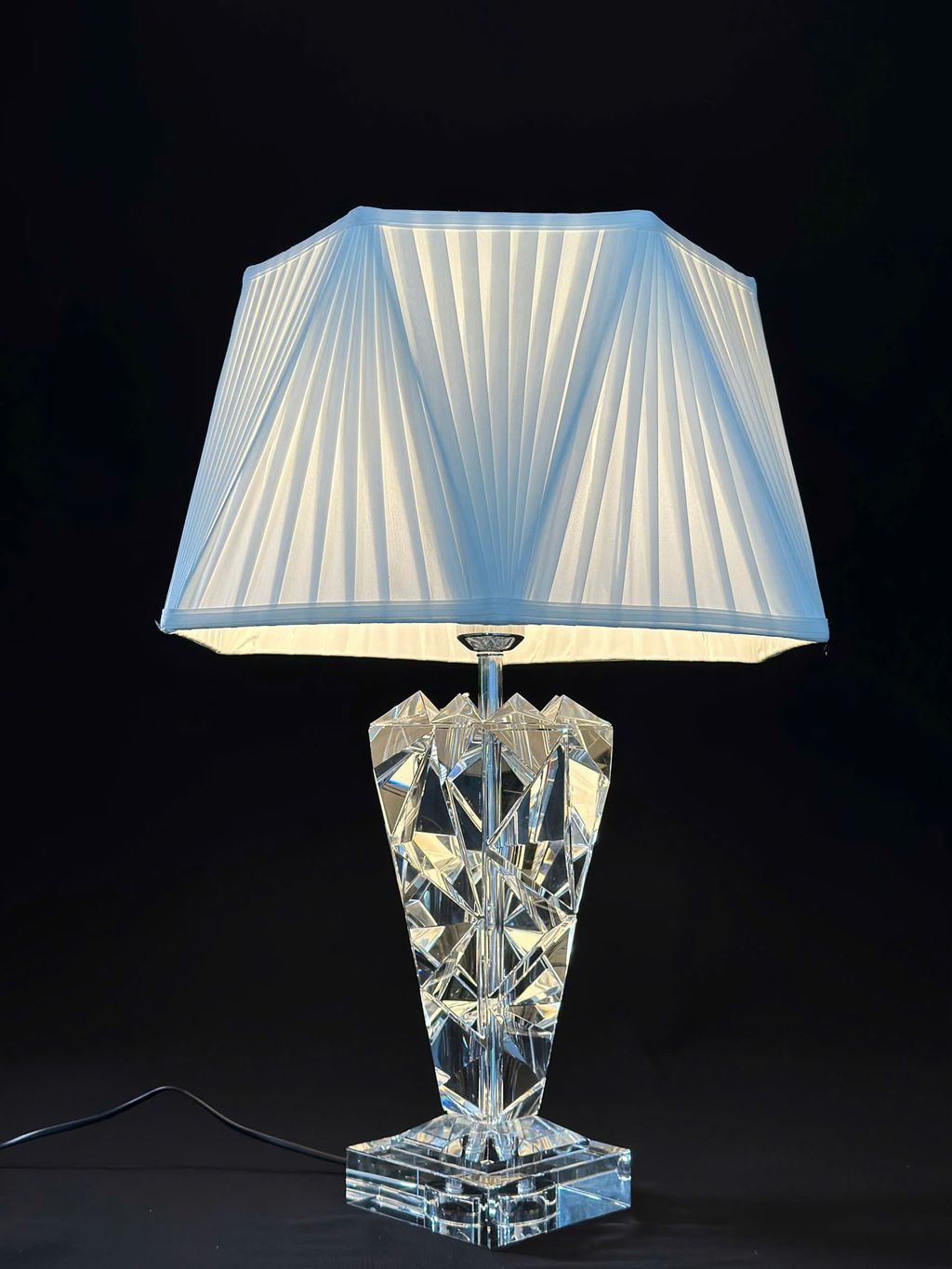 Chiếc đèn bàn pha lê cao cấp này gây ấn tượng mạnh mẽ ngay từ cái nhìn đầu tiên với chân đèn pha lê cắt khối đa diện độc đáo. Tinh xảo như một viên kim cương lấp lánh dưới ánh đèn. Mỗi góc cạnh pha lê phản chiếu ánh sáng lung linh, mang lại hiệu ứng thị giác cao cấp. Biến chiếc đèn trở thành điểm nhấn đầy nghệ thuật cho không gian phòng ngủ, phòng khách hay góc làm việc.
