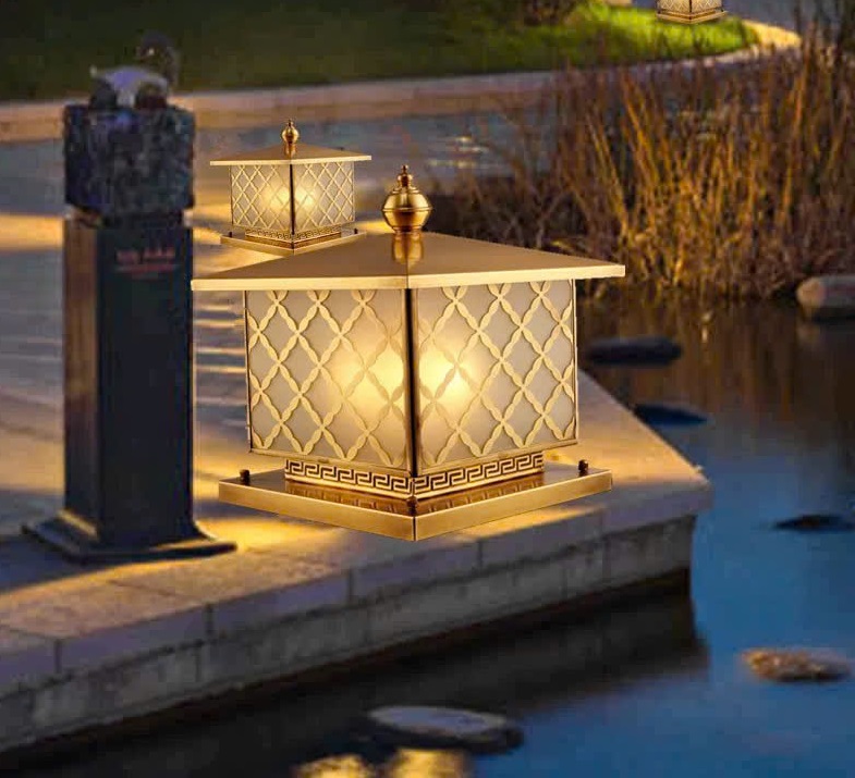 Đèn trụ cổng hoa văn mạ vàng không chỉ đóng vai trò chiếu sáng mà còn là một chi tiết trang trí nâng cao giá trị thẩm mỹ. Ban ngày, đèn như một vật phẩm trang trí sang trọng; ban đêm, ánh sáng dịu nhẹ tỏa ra qua lớp kính hoa văn tạo cảm giác ấm áp, an toàn và đầy cuốn hút.